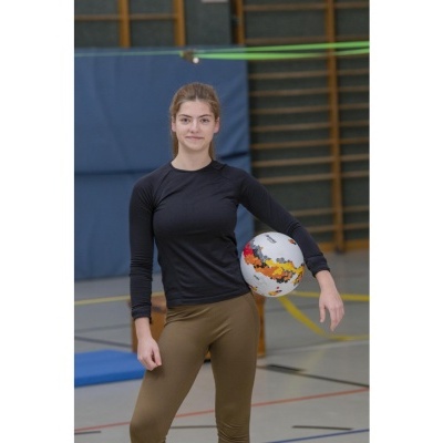 Jovem com roupas desportivas segurando uma bola colorida num ginásio