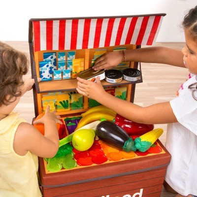 Banca de brinquedo com frutas e legumes de plástico coloridos e crianças a brincar