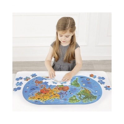 Criança a montar quebra-cabeças de mapa-múndi colorido sobre mesa branca