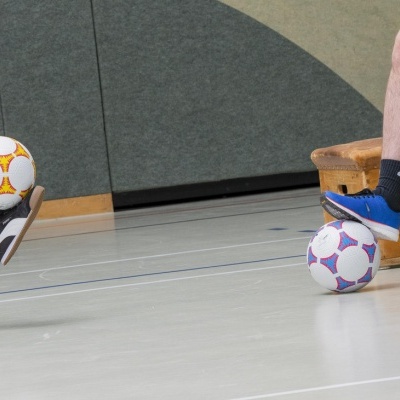Bolas de futebol de salão coloridas em ginásio junto a banco de madeira BENZ Geräte