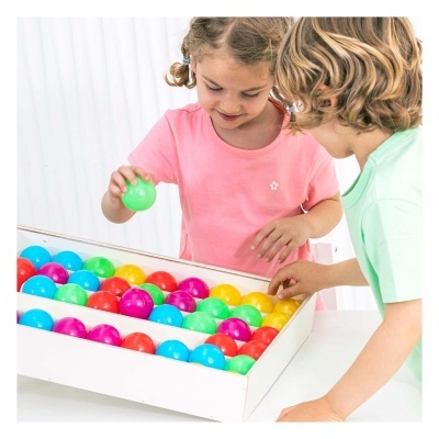 Crianças a brincar com bolas coloridas de plástico em caixa branca