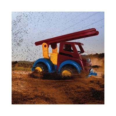 Caminhão de brinquedo colorido a mover-se na lama, terra a voar