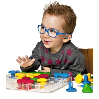 Criança com óculos azuis a brincar com brinquedo educativo de formas coloridas em plástico