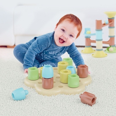 Bebé a brincar com brinquedo de encaixe colorido sobre tapete branco