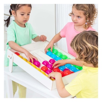 Jogo de mesa com bolas coloridas e crianças a brincar