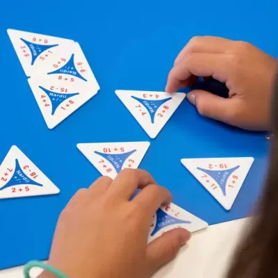 Peças triangulares de jogo educativo com operações matemáticas em cima de mesa azul