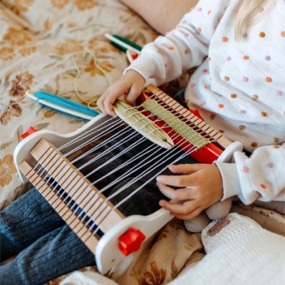 Criança a usar tear manual infantil colorido na cama