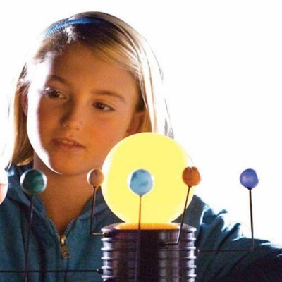 Menina com casaco azul a observar modelo do sistema solar colorido