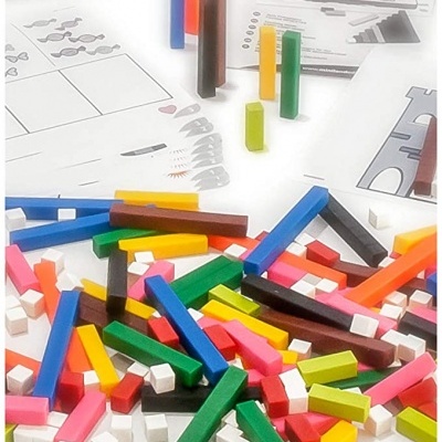 Peças de construção coloridas em plástico sobre mesa com desenhos técnicos e aviso de segurança.