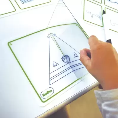 Cartões de jogo educativo com desenhos geométricos e mão de criança a escrever