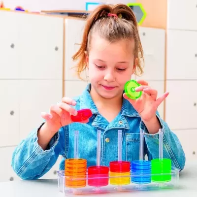 Criança a brincar com brinquedo educativo de empilhar discos coloridos