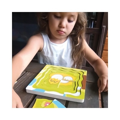 Criança a montar puzzle de madeira com figura de doce amarelo