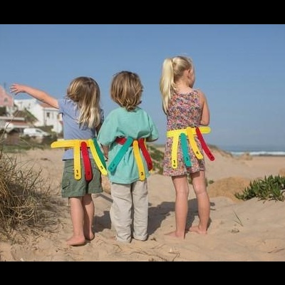 Três crianças na praia com cintos de segurança coloridos de velcro