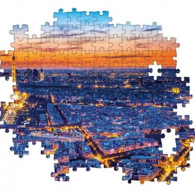 Puzzle parcialmente montado com vista aérea noturna de cidade iluminada ao pôr do sol