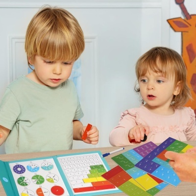 Duas crianças a jogar um jogo educativo colorido com cartas e quadro branco