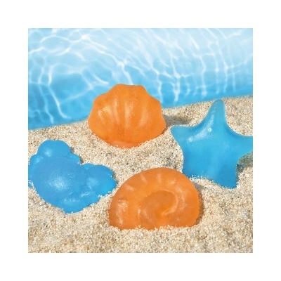 Brinquedos de praia em forma de concha, estrela do mar, caracol e cavalo-marinho sobre areia junto a água.