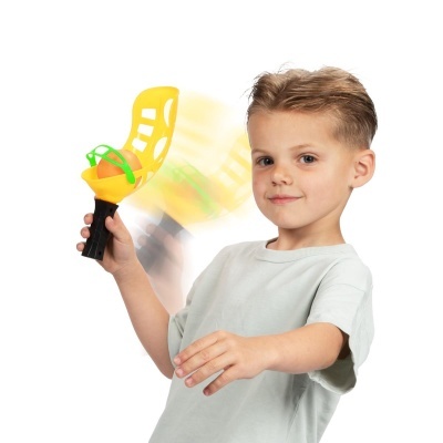 Criança segurando brinquedo lançador amarelo e verde com bola laranja
