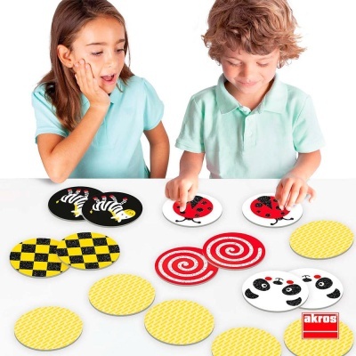 Duas crianças a jogar jogo da memória com peças redondas coloridas e padrões de animais e cores