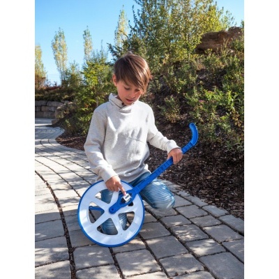 Criança a usar roda de medição azul em caminho de pedra ao ar livre