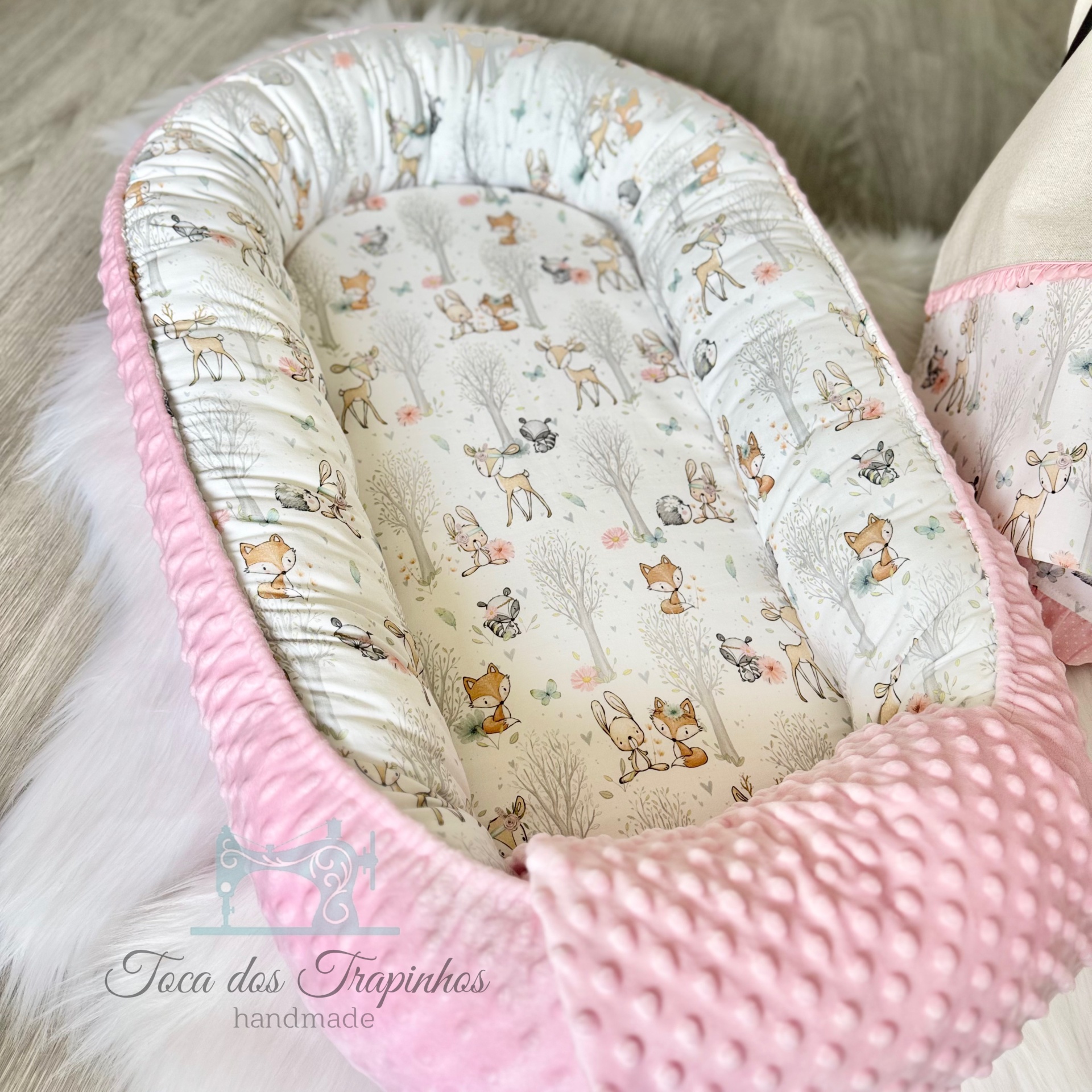 Ninho para bebé com padrão de animal e borda rosa texturizada