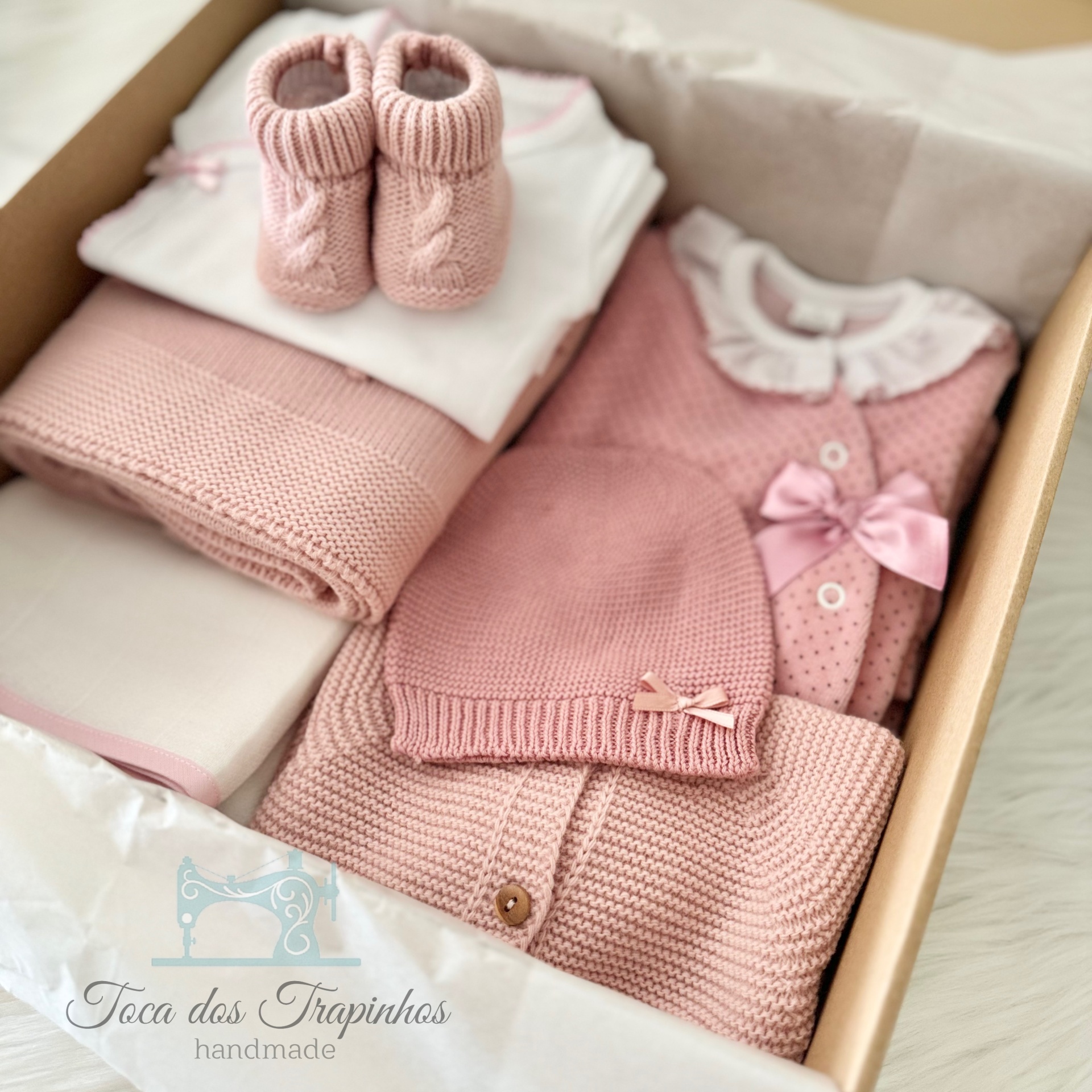 Conjunto de roupa de bebé rosa em caixa com sapatinhos, body, manta, babygrow e gorro