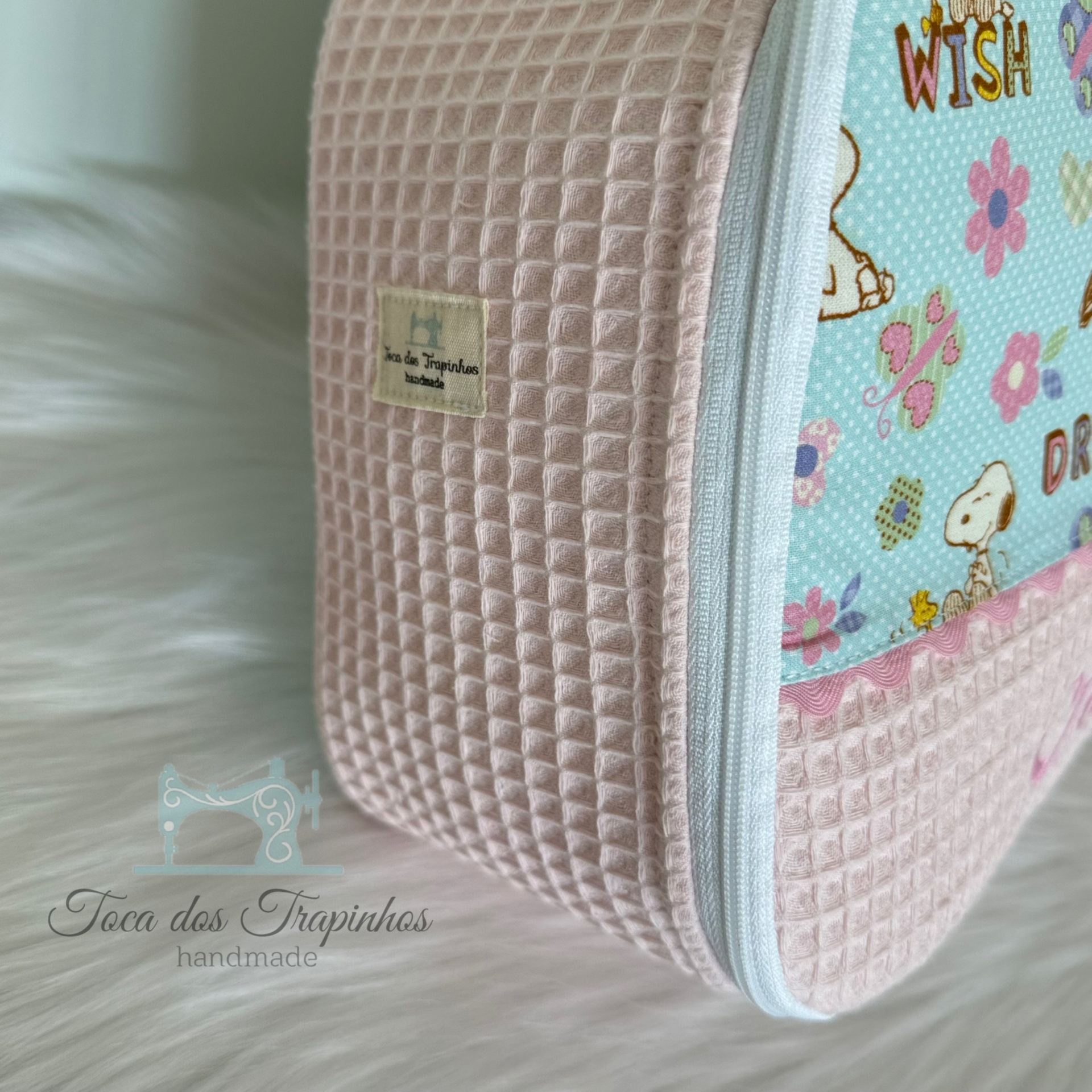 Bolsa rosa claro com textura quadriculada e tecido azul estampado com flores e personagens