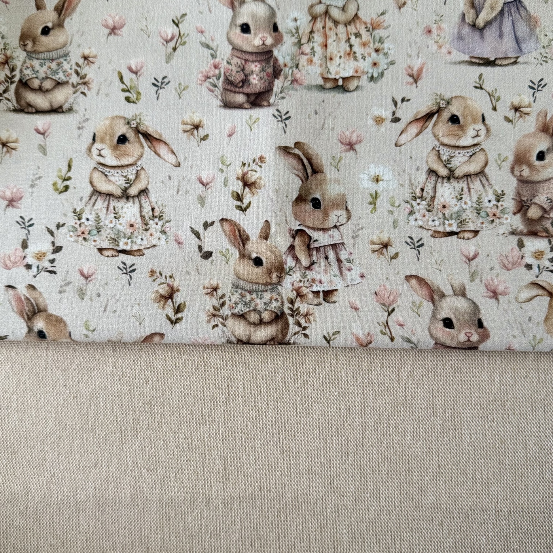 Tecido com padrão de coelhinhos vestidos e flores em tons suaves
