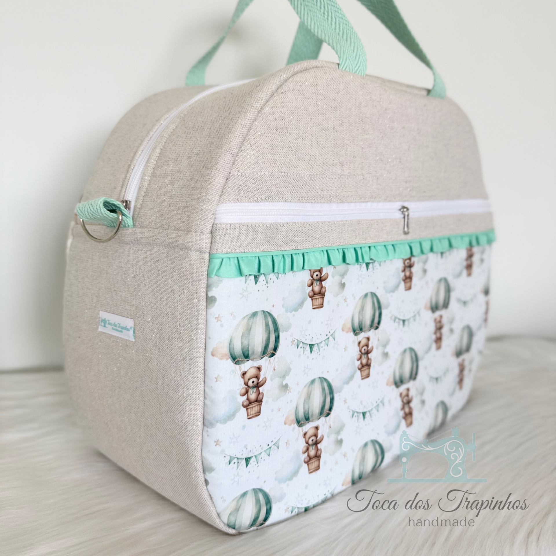 Bolsa infantil bege com estampado de ursinhos em balões e detalhes verdes.