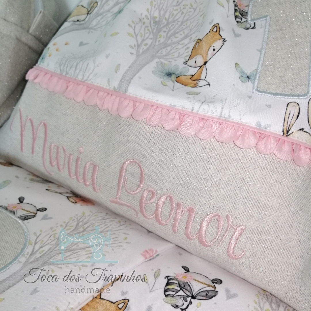 Almofada decorativa em tecido com padrão de animais da floresta e bordado rosa com o nome Maria Leonor.