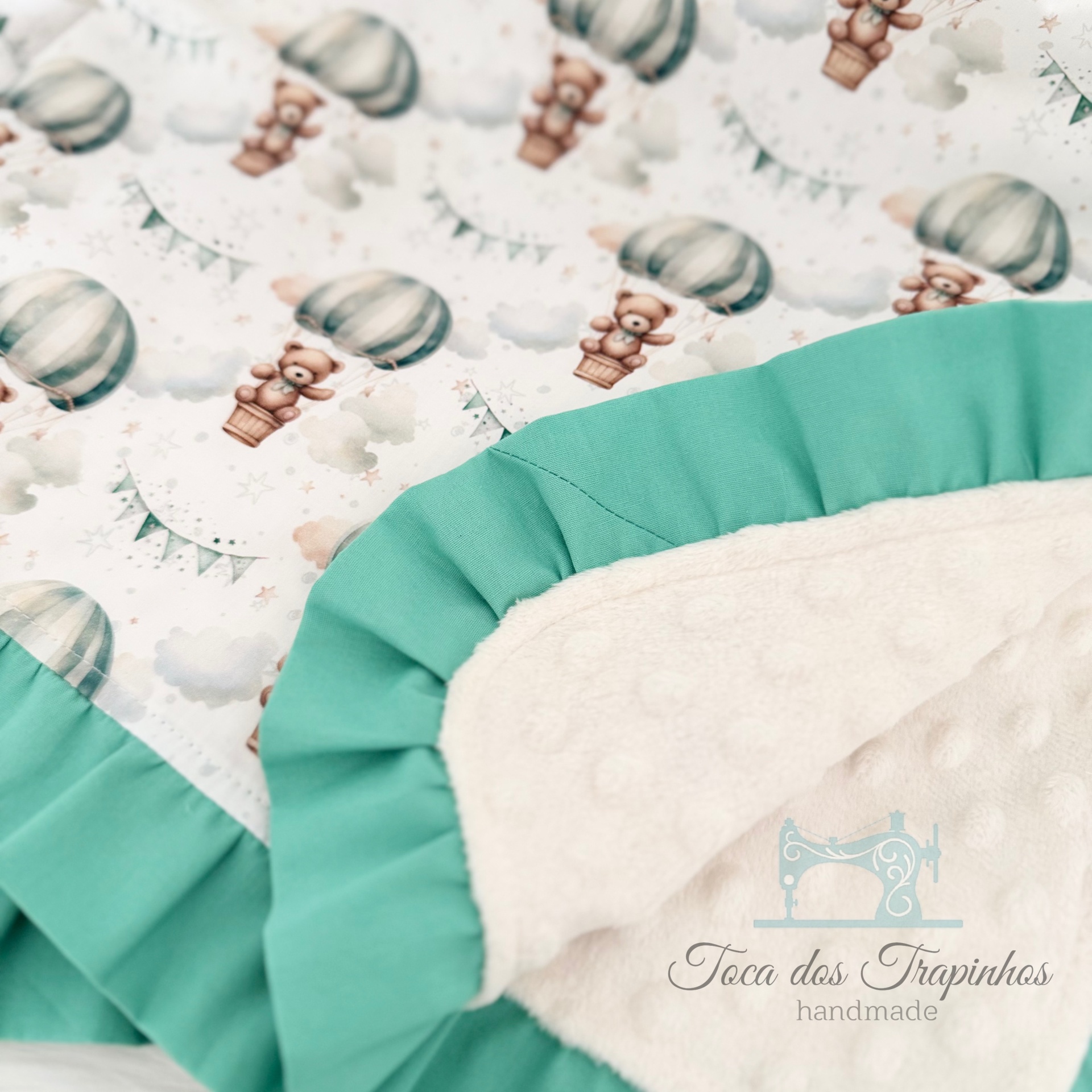 Manta infantil com ursos em balões de ar quente, borda verde e verso branco texturizado