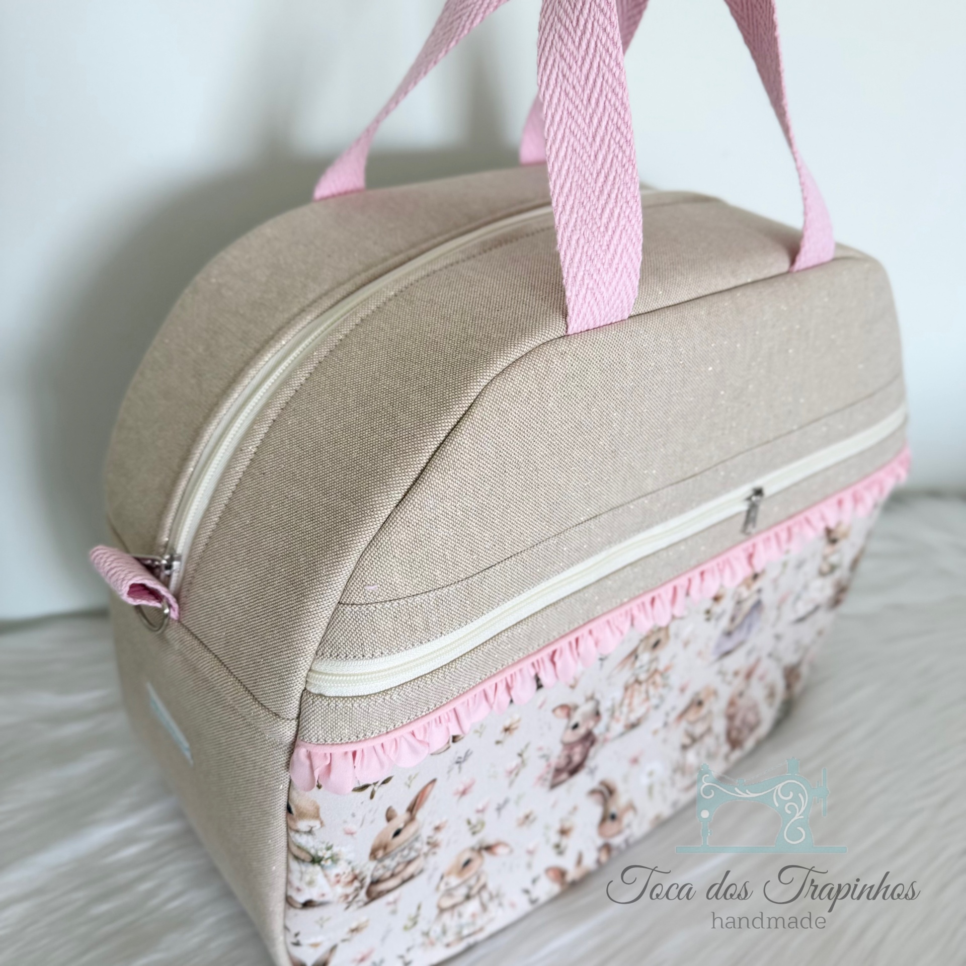 Mala bege com alças rosas, padrão de coelhos e franja cor de rosa