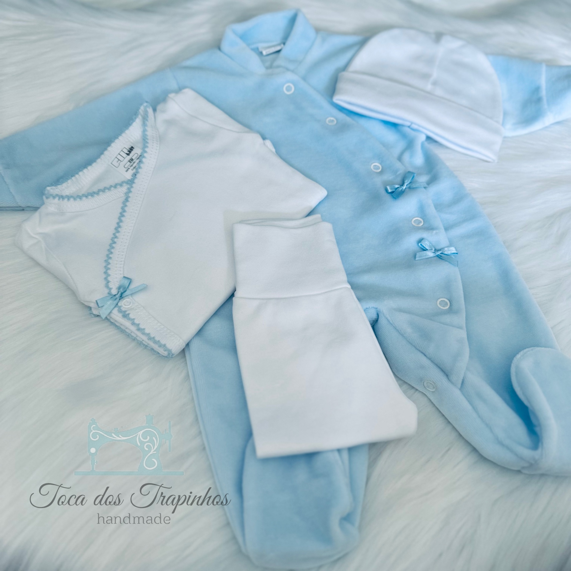 Conjunto de roupa para bebé azul e branca sobre fundo branco felpudo