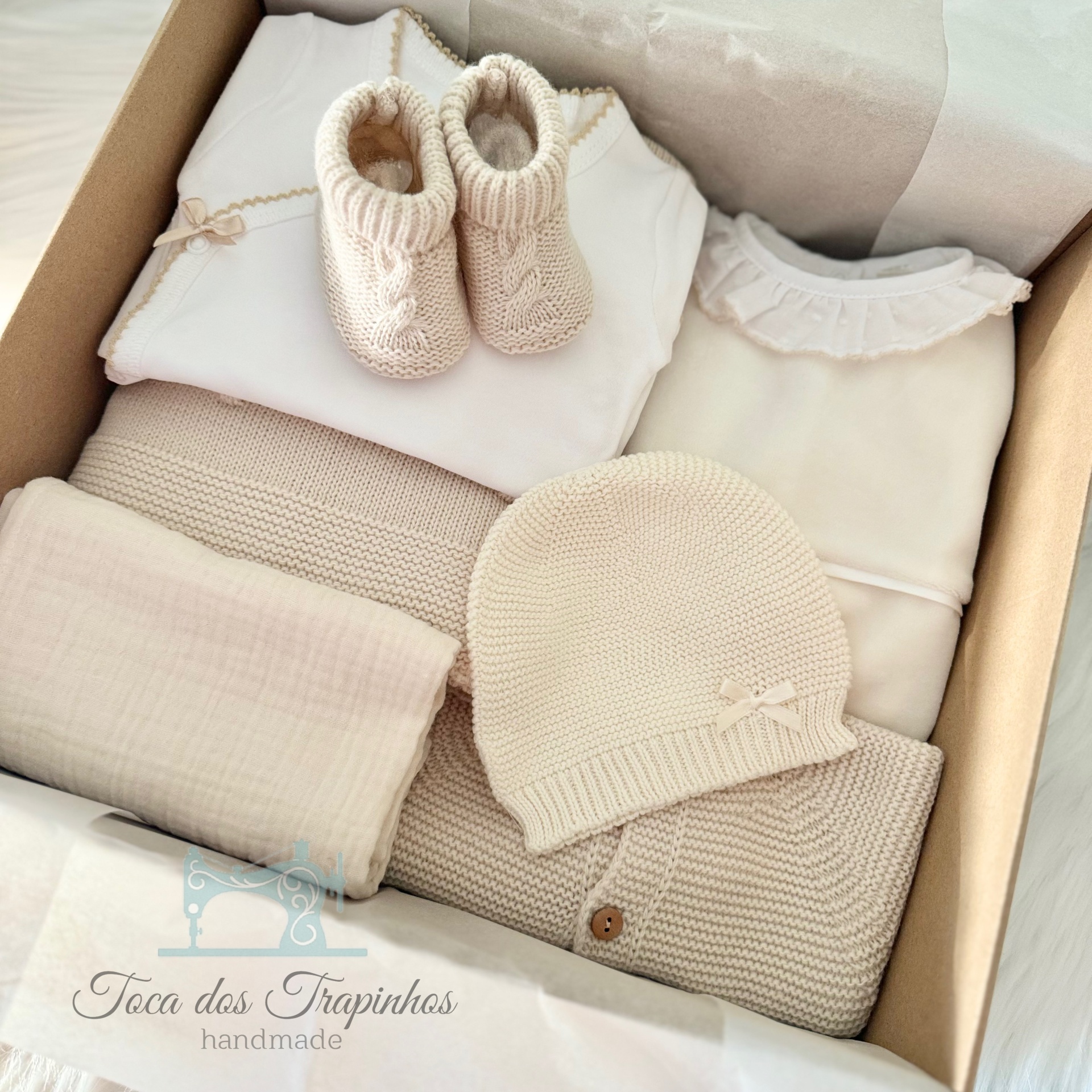Conjunto de roupa de bebé em caixa com sapatinhos, roupa e touca em tons neutros