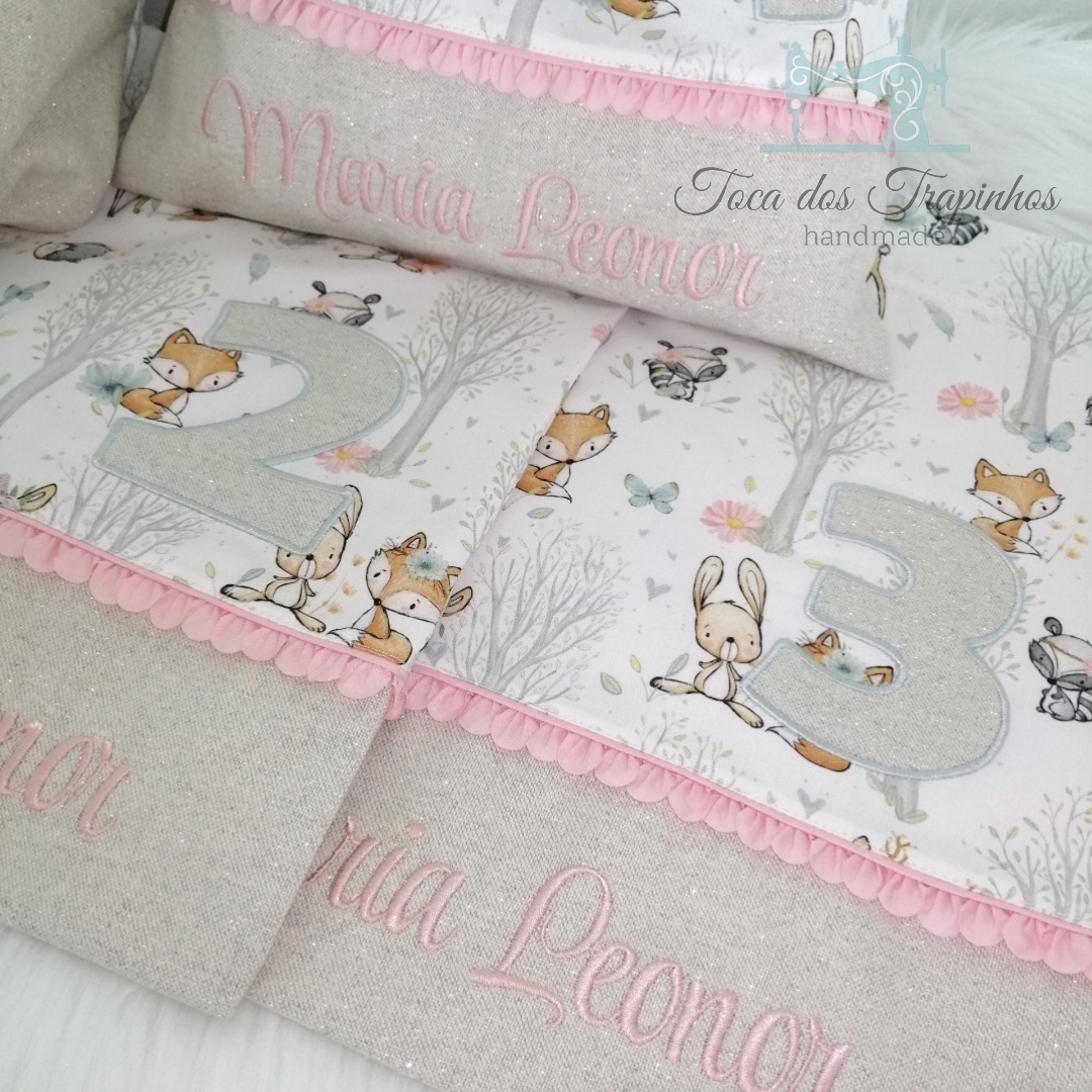 Produtos têxteis para bebé com padrão infantil de animais, números e bordado rosa com nome Maria Leonor.