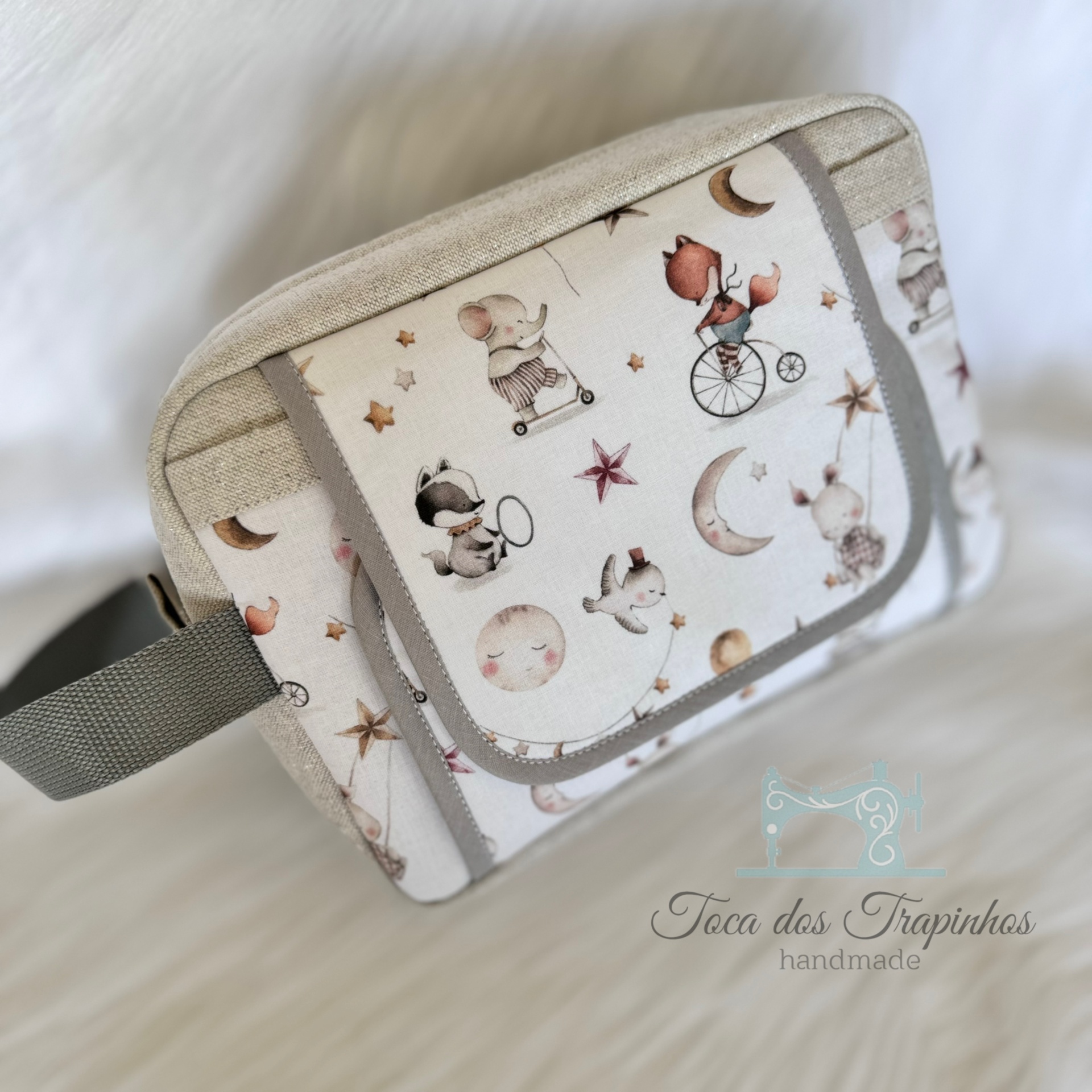 Bolsa artesanal com decoração de animais e estrelas em tecido branco de fundo