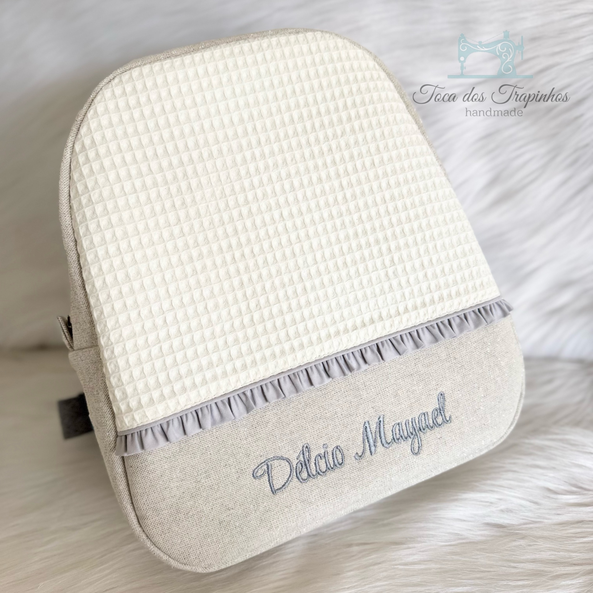 Mochila artesanal bege e branco com texto bordado Délcio Mayanel
