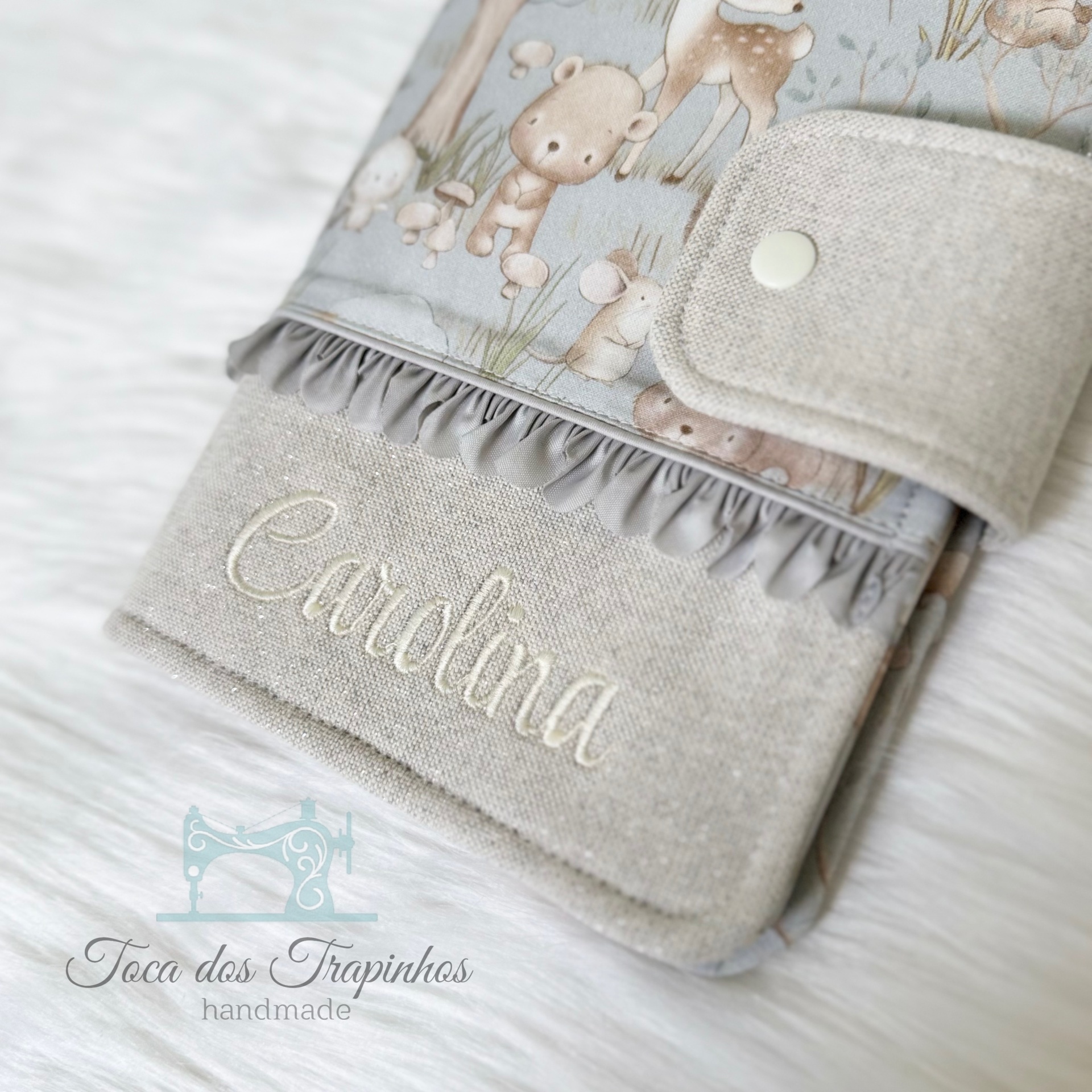 Capa de tecido cinzenta e bege com nome Carolina bordado e padrão de animais
