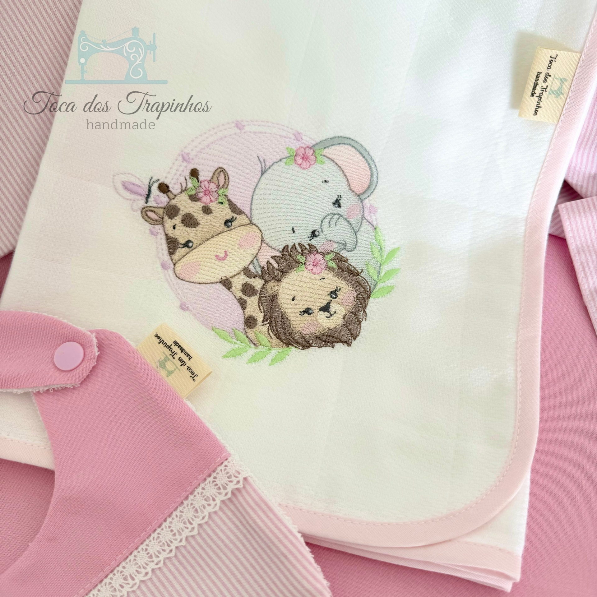 Toalha infantil branca com bordado de girafa, elefante e leão e rebordo rosa