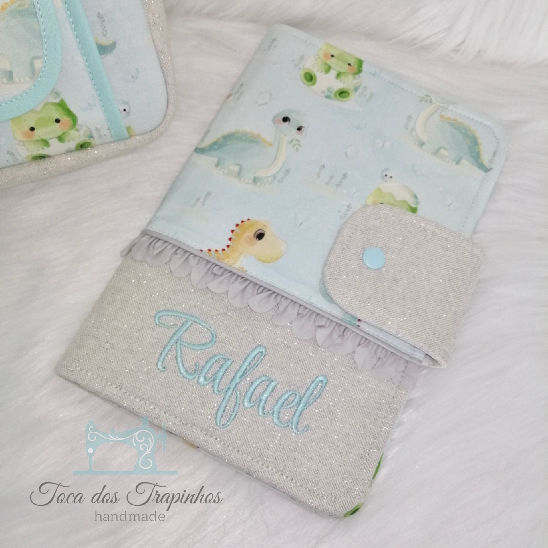 Capa para caderneta de vacinação com estampa de dinossauros e nome Rafael bordado.