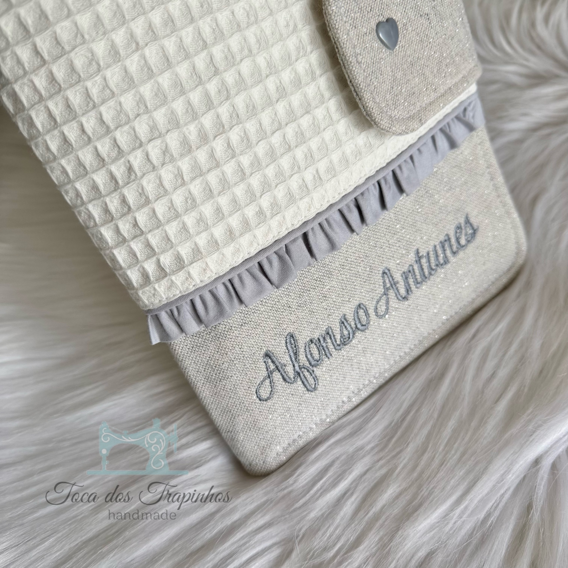 Capa artesanal branca com padrão em relevo e bordado azul com o texto Afonso Antunes.
