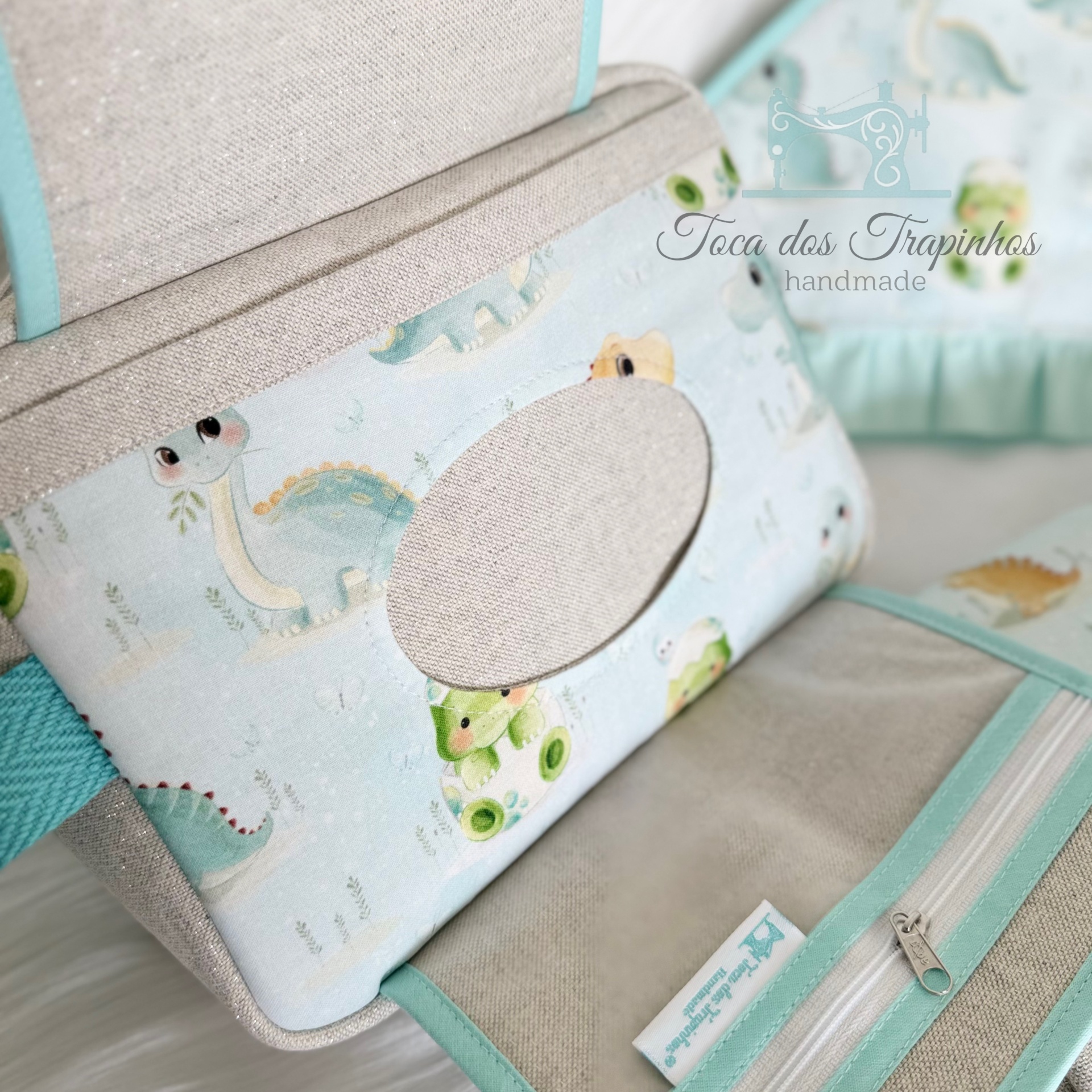 Bolsa artesanal bege e azul com padrão de dinossauros e etiqueta Toca dos Trapinhos handmade