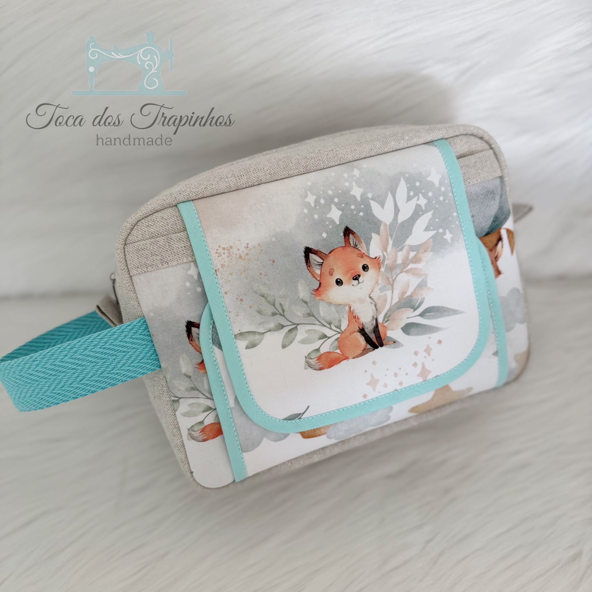 Bolsa pequena com estampa de raposa e folhagem, detalhes azuis e cinza.