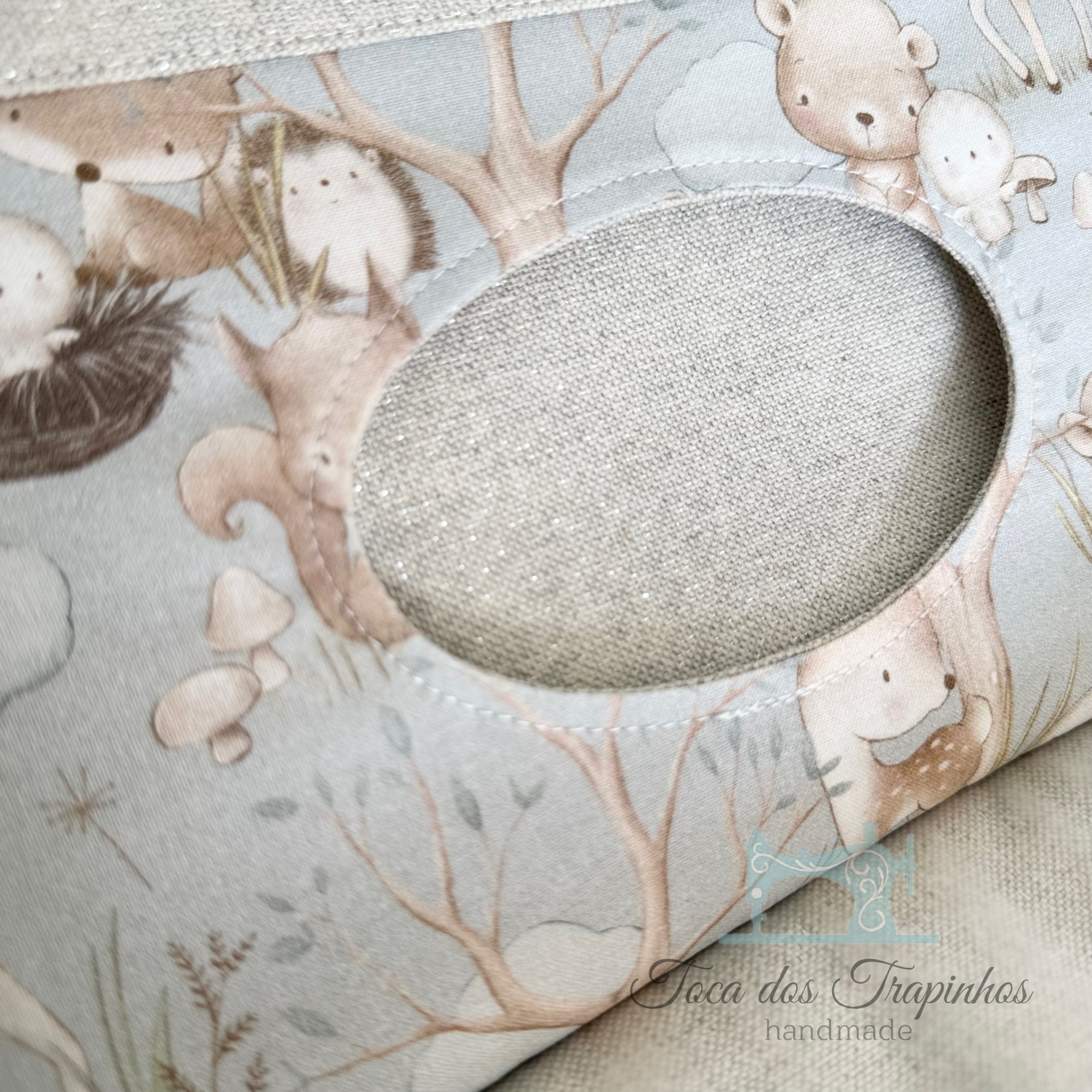 Capa em tecido infantil com padrão de animais e recorte oval