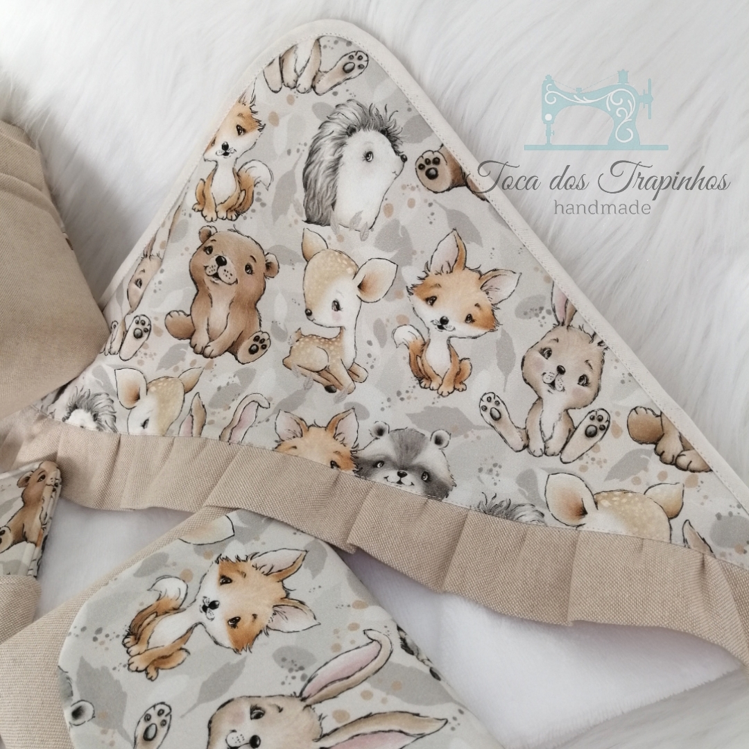 Capa de banho branca com padrão de animais e barra franzida bege em fundo branco felpudo