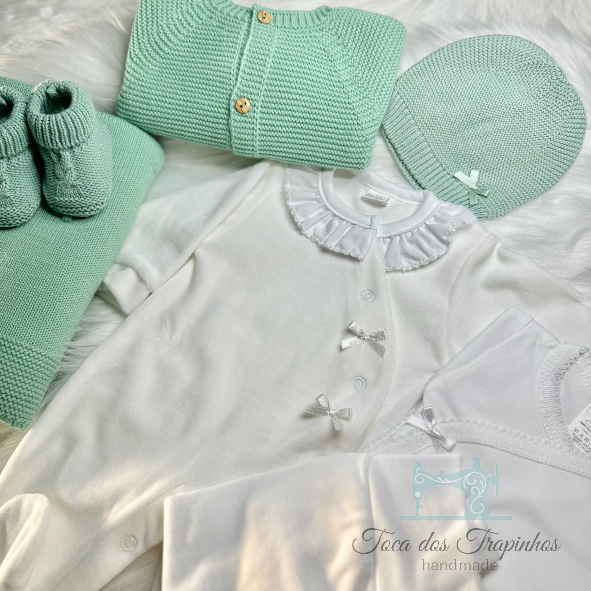 Conjunto de roupa de bebé em verde água e branco com botas, casaco, touca e body com folho e laços