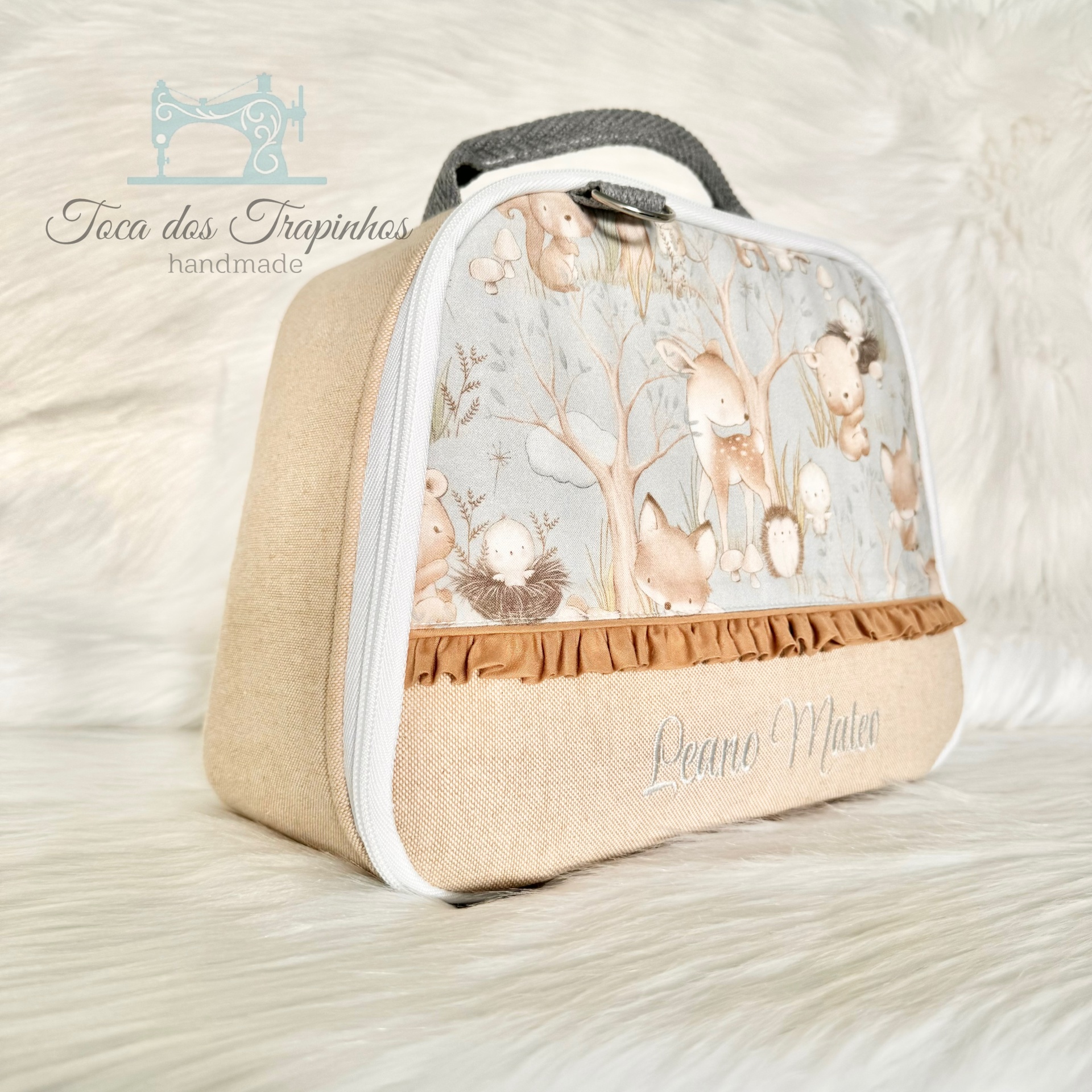 Mala infantil bege e azul claro com padrão de animais da floresta e nome bordado