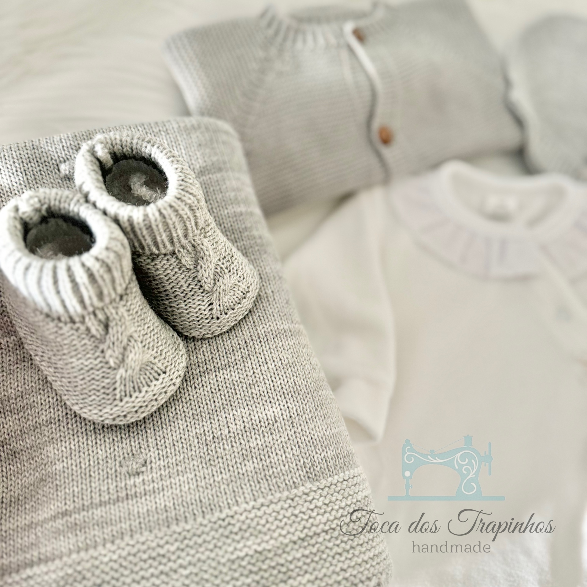 Conjunto de roupa de bebé em malha cinzenta e branca com botinhas e casaco