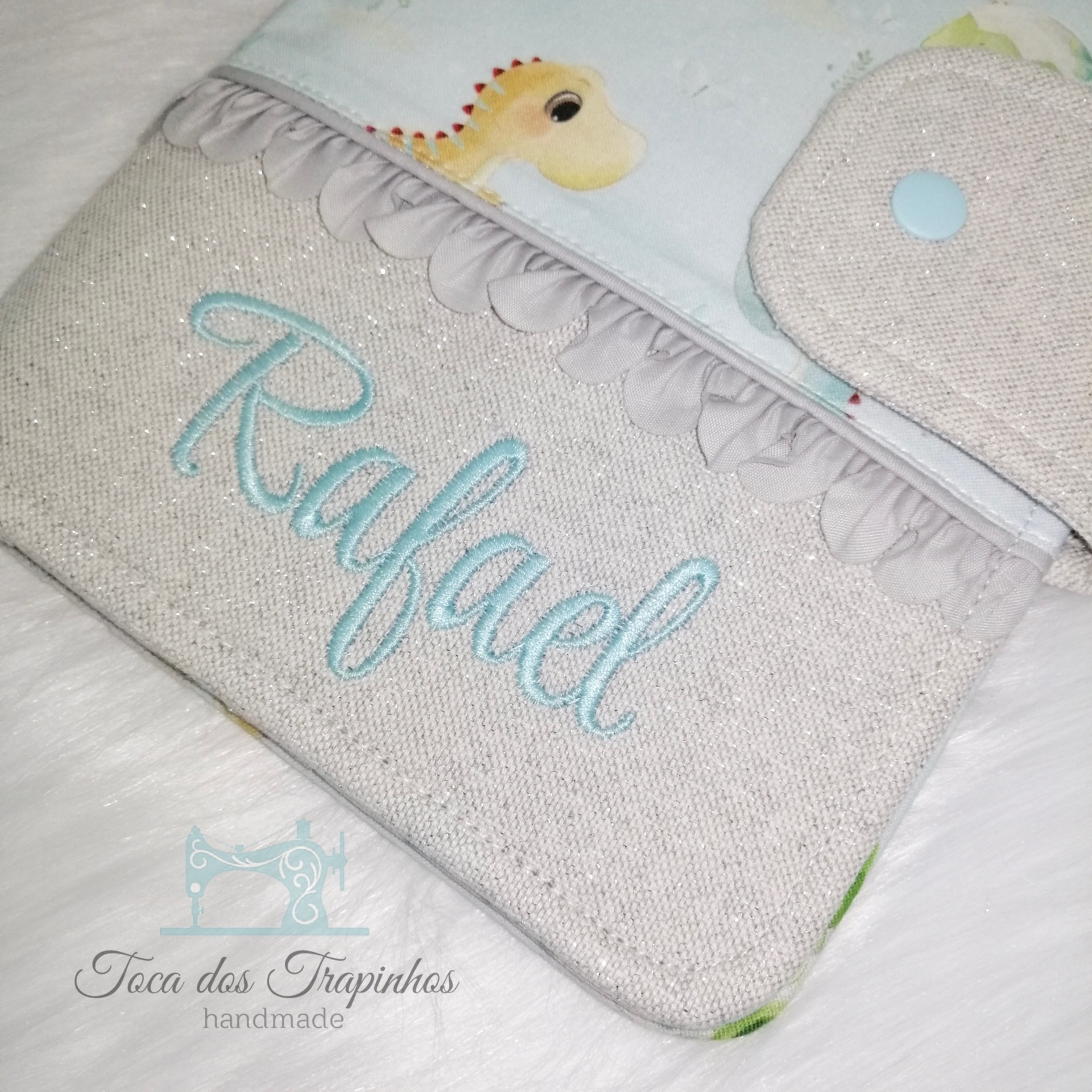 Bolsa de tecido bege claro com nome Rafael bordado azul e detalhe de girafa