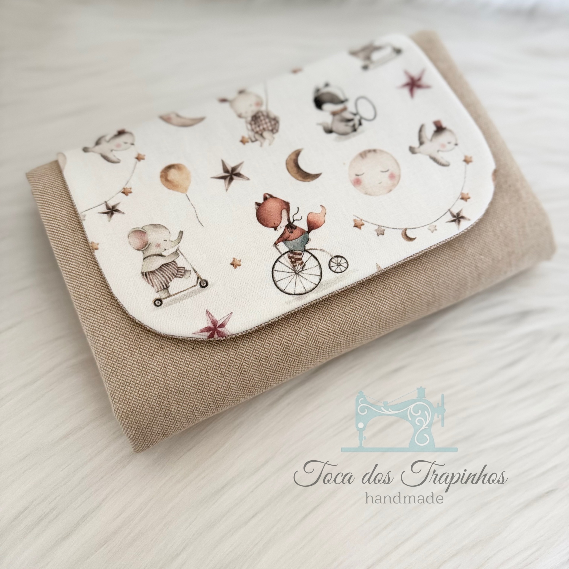 Manta dobrada com padrão infantil e logótipo 'Toca dos Trapinhos handmade'