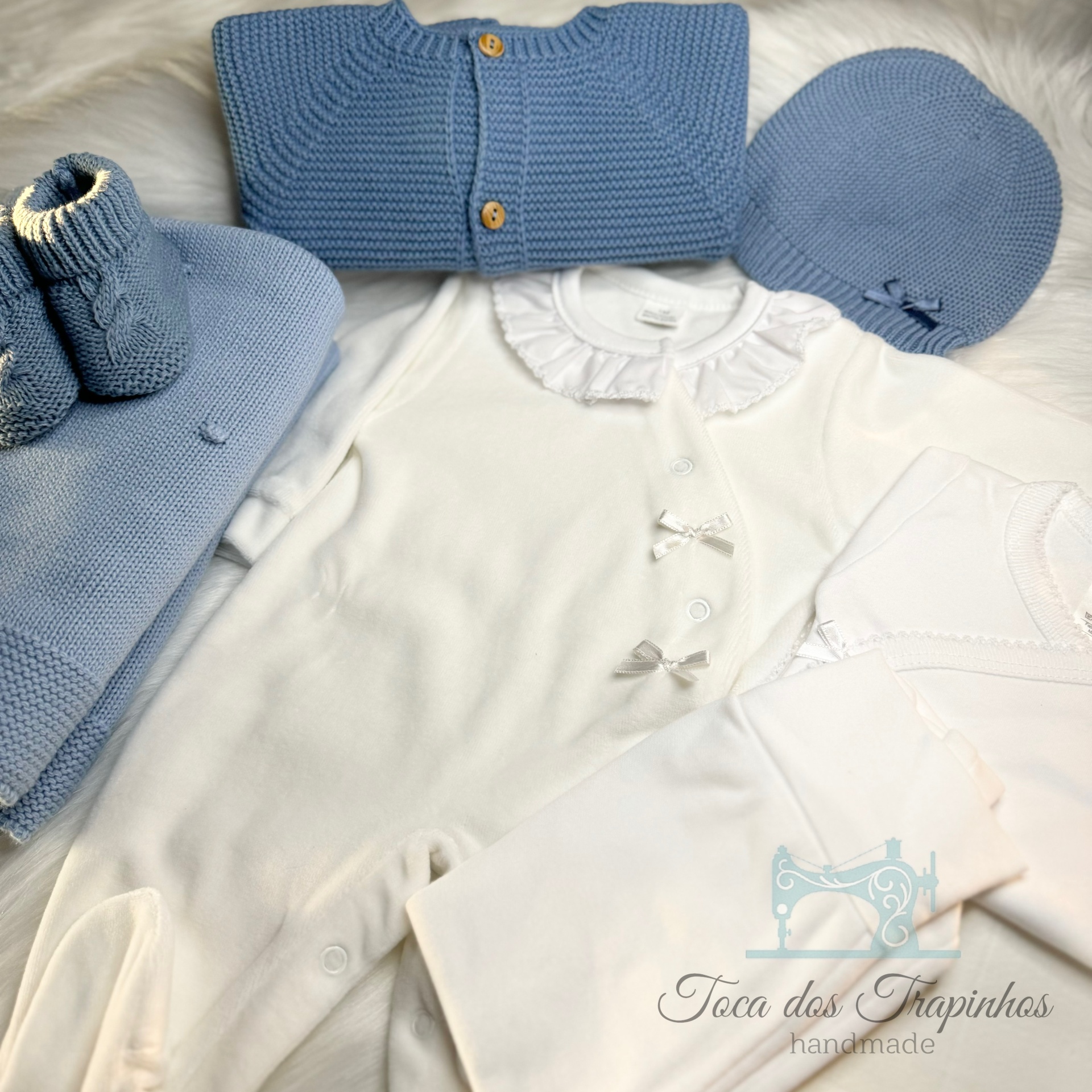Conjunto de roupa de bebé azul e branco incluindo macacão, casaco, gorro, botinhas e manta em tecido de malha